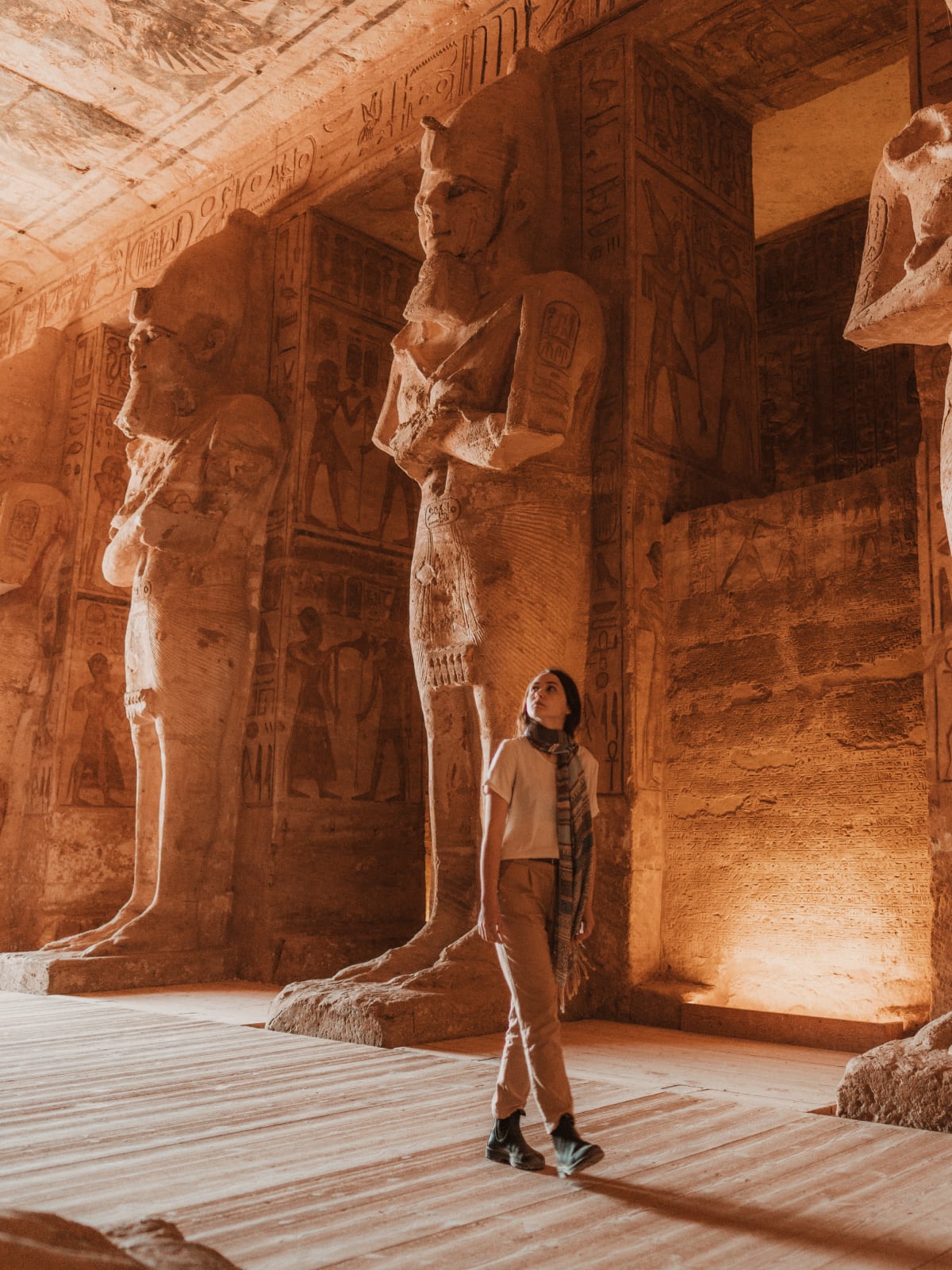 Traveller looking up at towering ancient Egyptian statues inside the temple hall at Abu Simbel, Egypt.