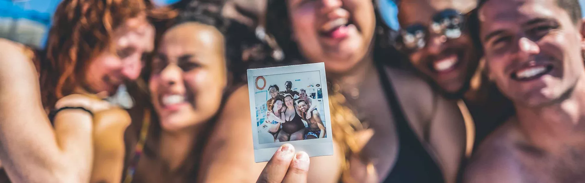 Group Holding Up Polaroid Photo On A Reunion Trip