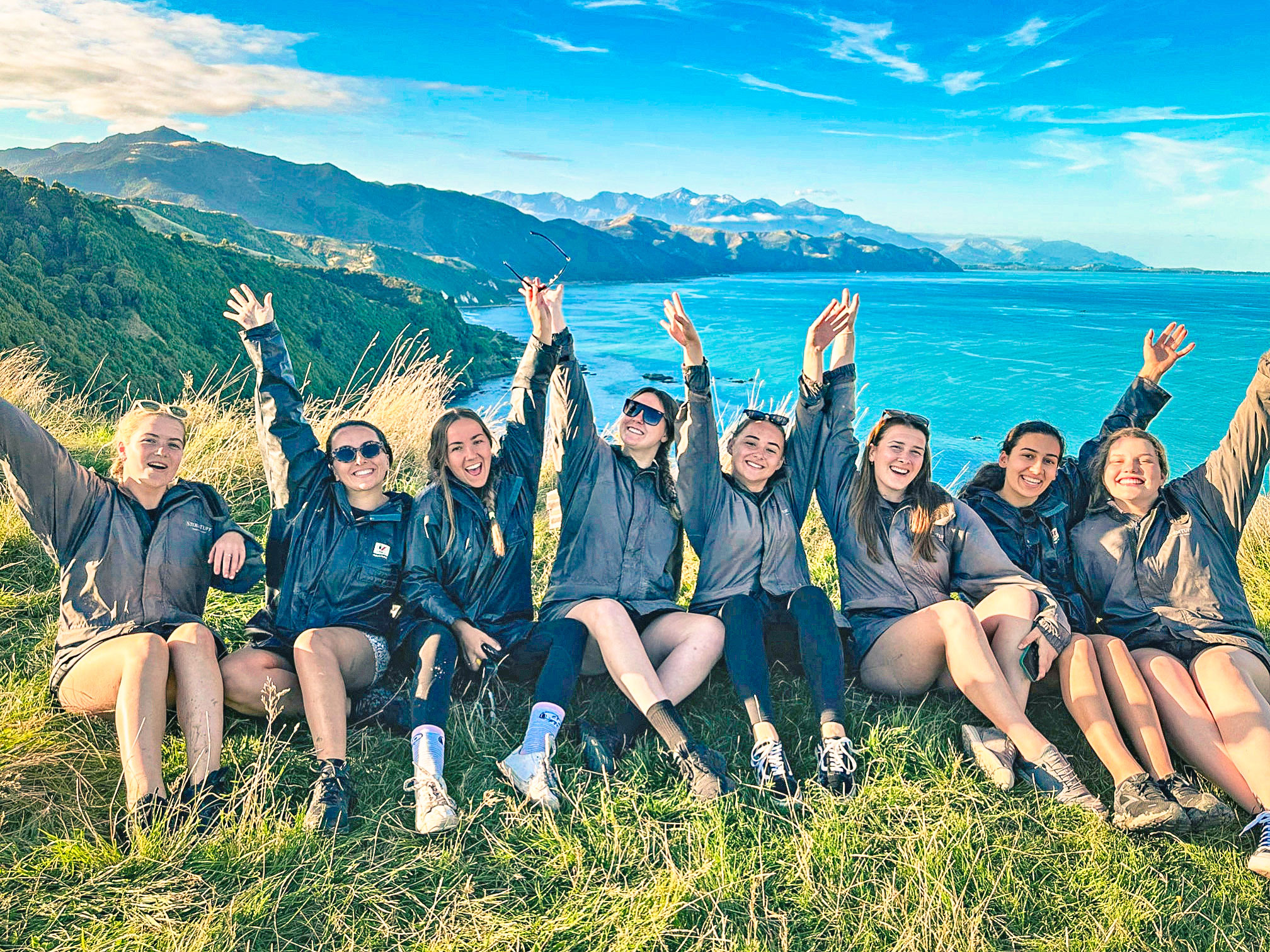 Travellers sitting by a view point with ocean and mountains in Kaikoura, New Zealand