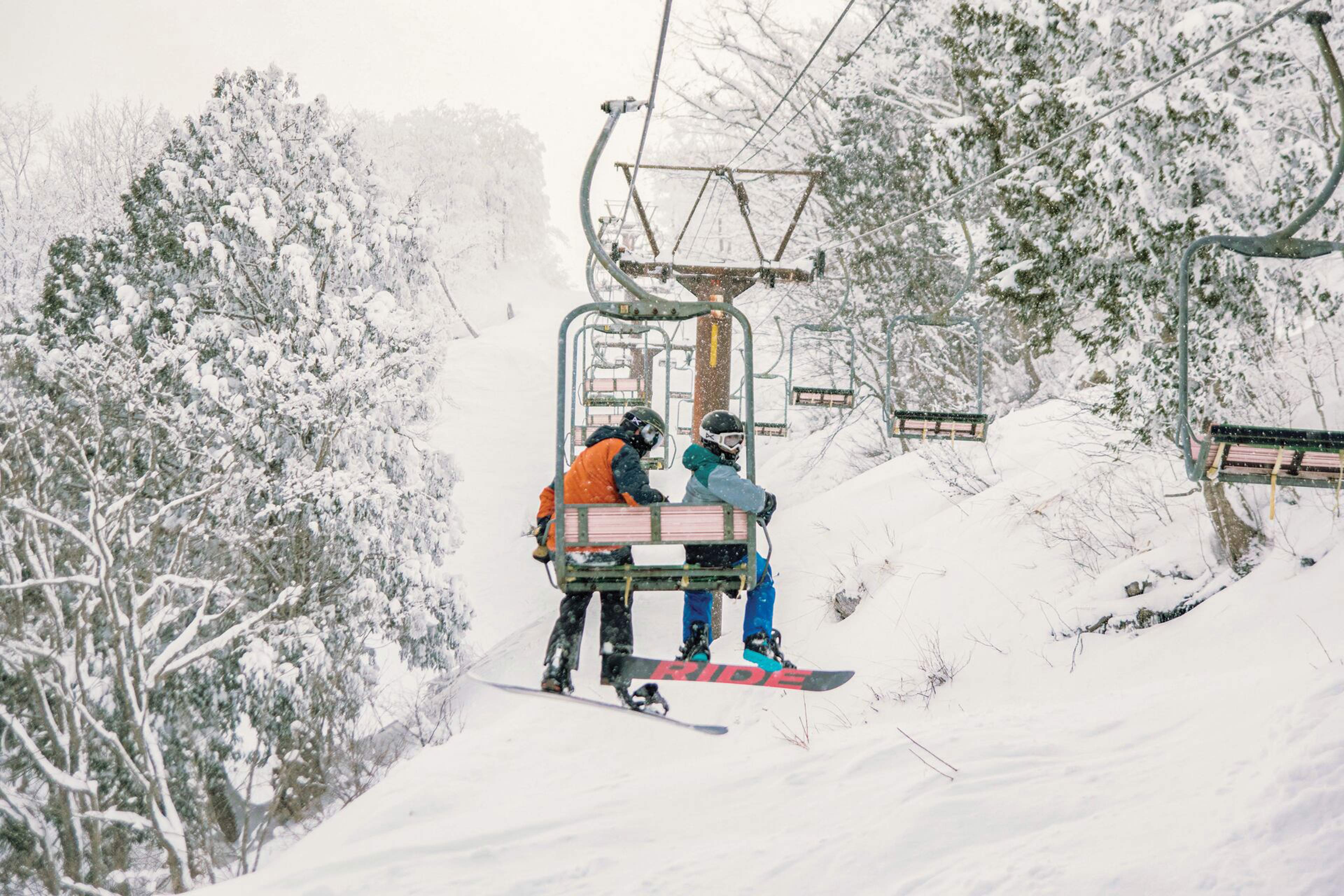 Two people enjoy a snowy day of snowboarding in Hakuba, Japan.