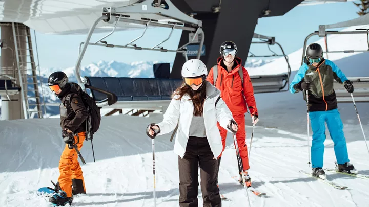 Travellers on skis and snowboard after leaving a ski lift in Hopfgarten, Austria