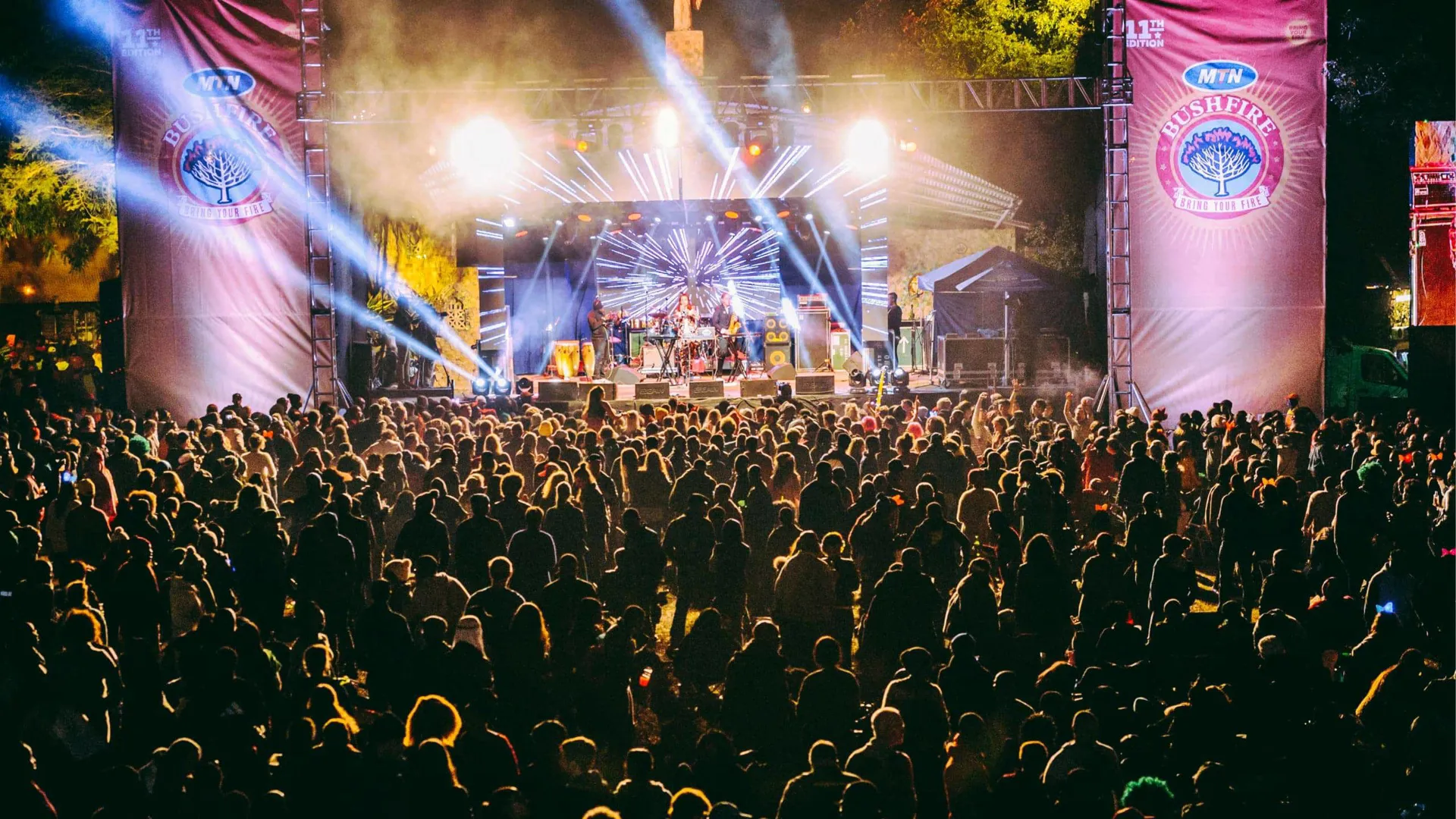 Large crowd watching a live performance on the main stage at MTN Bushfire Festival in Eswatini with dramatic blue stage lighting at night - Contiki Kruger Safari & Bushfire Festival