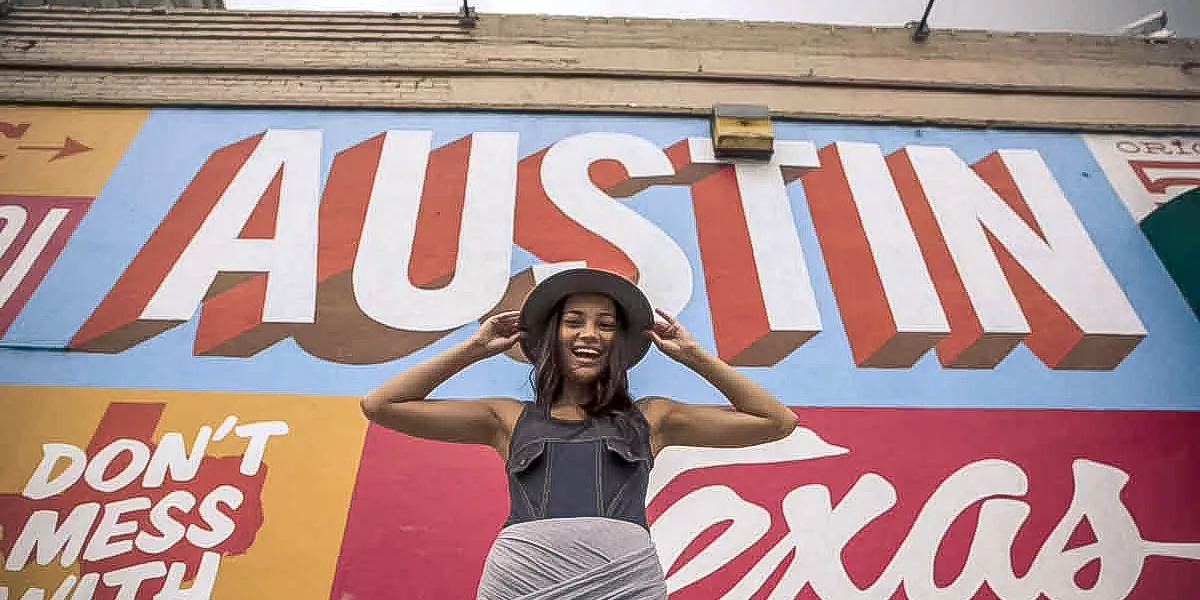 Young Woman Standing In Front Of Large Texas Sign