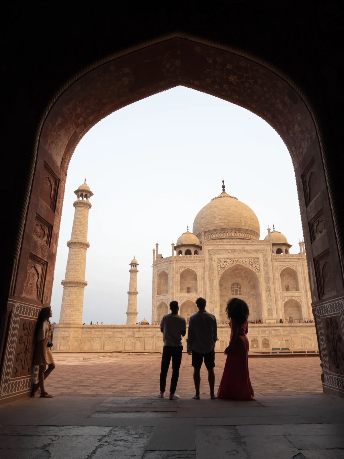 Travellers standing beneath an archway overlooking the Taj Mahal in Agra, India.