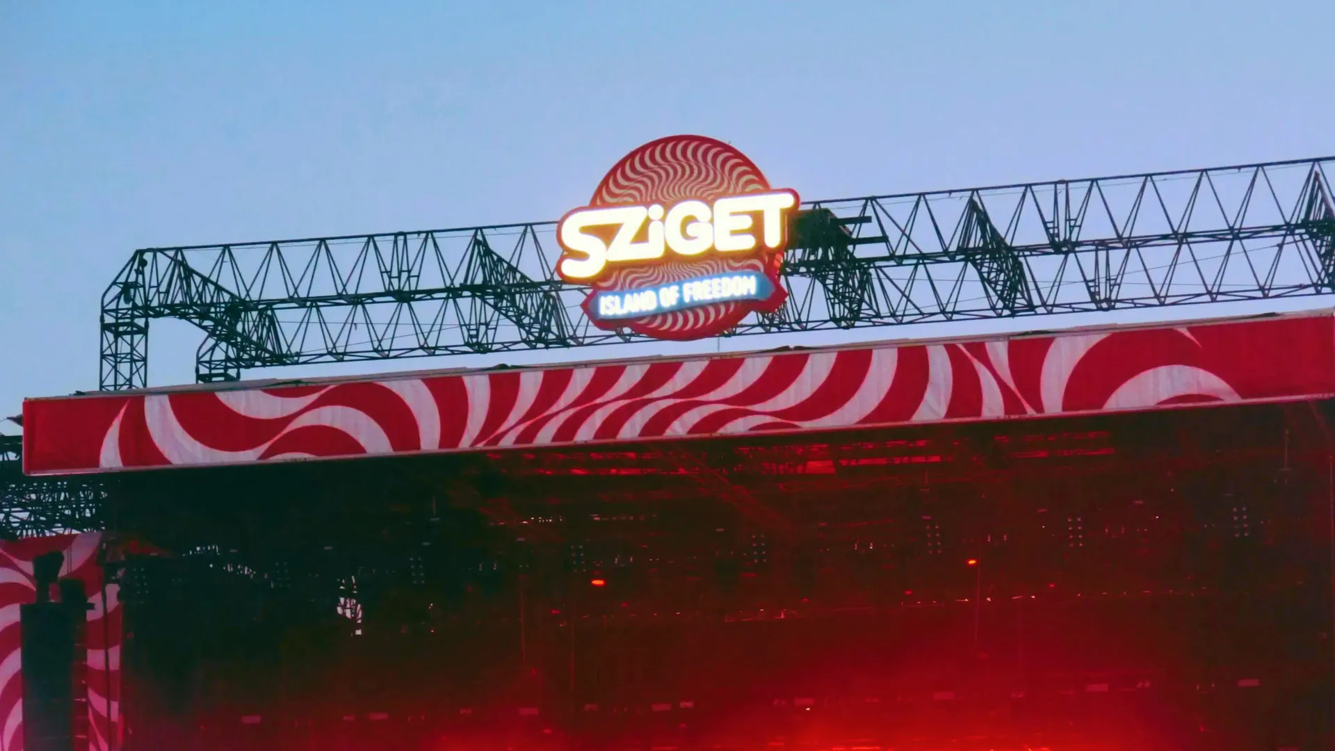 Sziget Festival main stage at dusk in Budapest Hungary with illuminated logo and red swirl stage design - Contiki Europe Festival Tour
