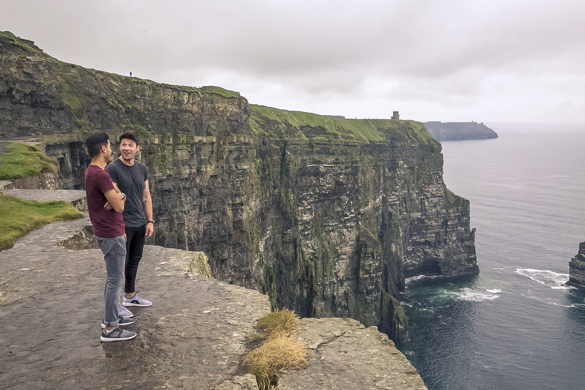 Two Friends Talking And Smiling At The Top Of A Clief