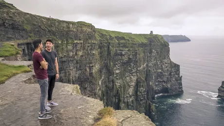 Two Friends Talking And Smiling At The Top Of A Clief