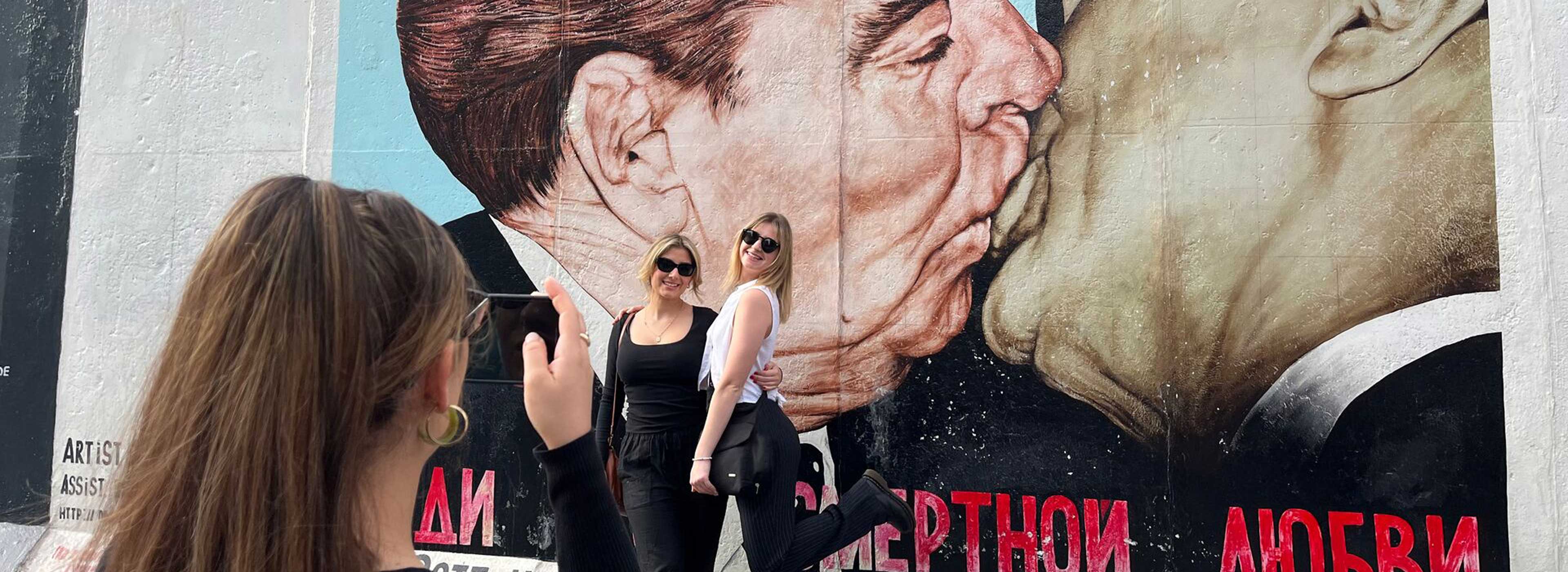 Travellers in front of East Side Gallery mural, Berlin, Germany