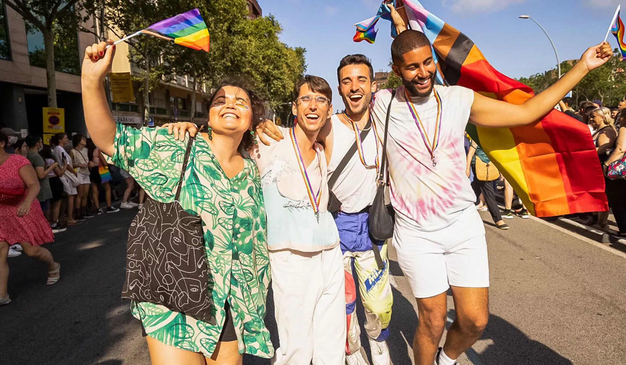 Friends holding the pride flag while walking the street smiling