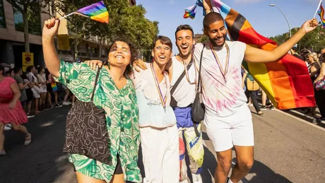Friends holding the pride flag while walking the street smiling
