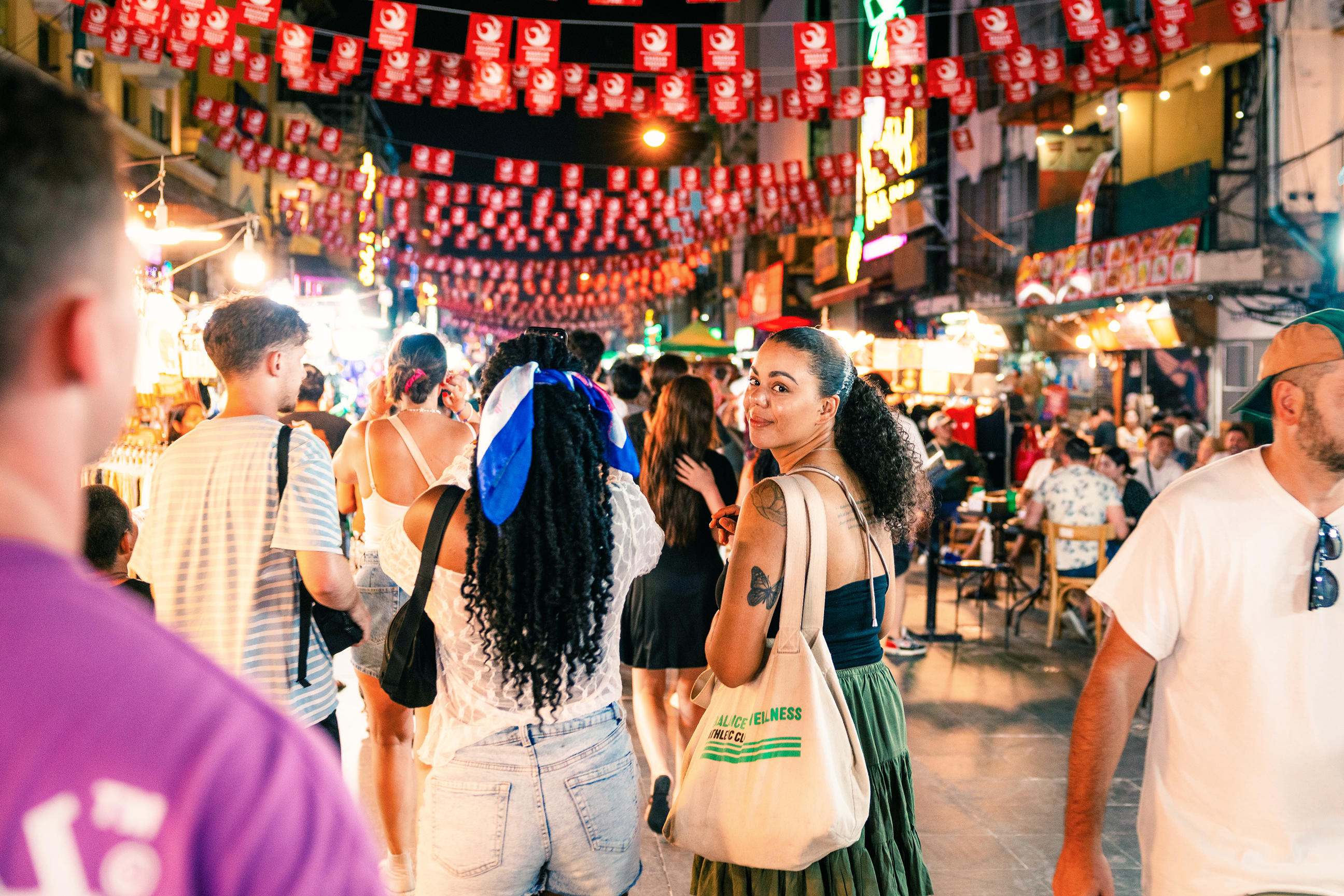 Traveller walking on Khao San road, looking back at camera, Bangkok, Thailand