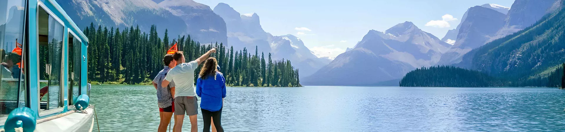 Three People Looking Over Lake And Mountains Man Pointin To Sky