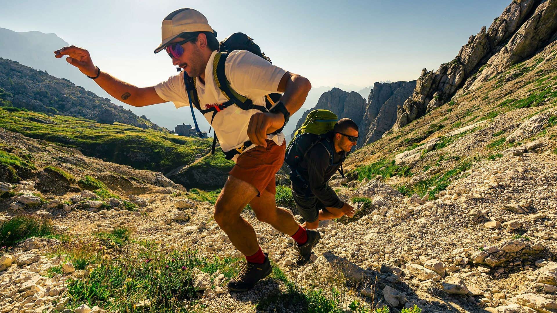 Hikers with backpacks climb a rocky trail through the dramatic peaks of the Dolomites, Italy.