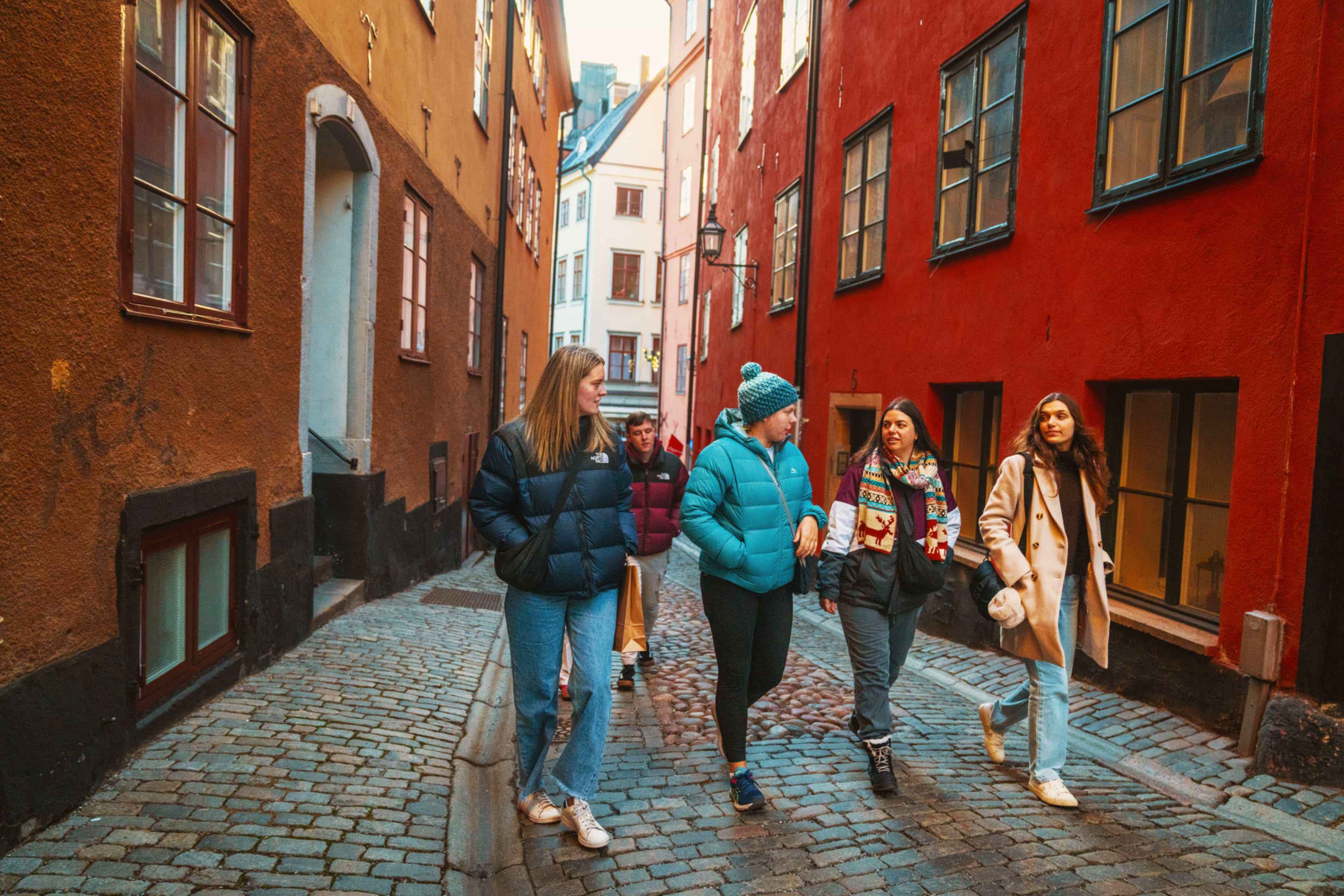 Group of travellers walking a cobbled street lined with colourful buildings in Gamla Stan, Stockholm, Sweden.