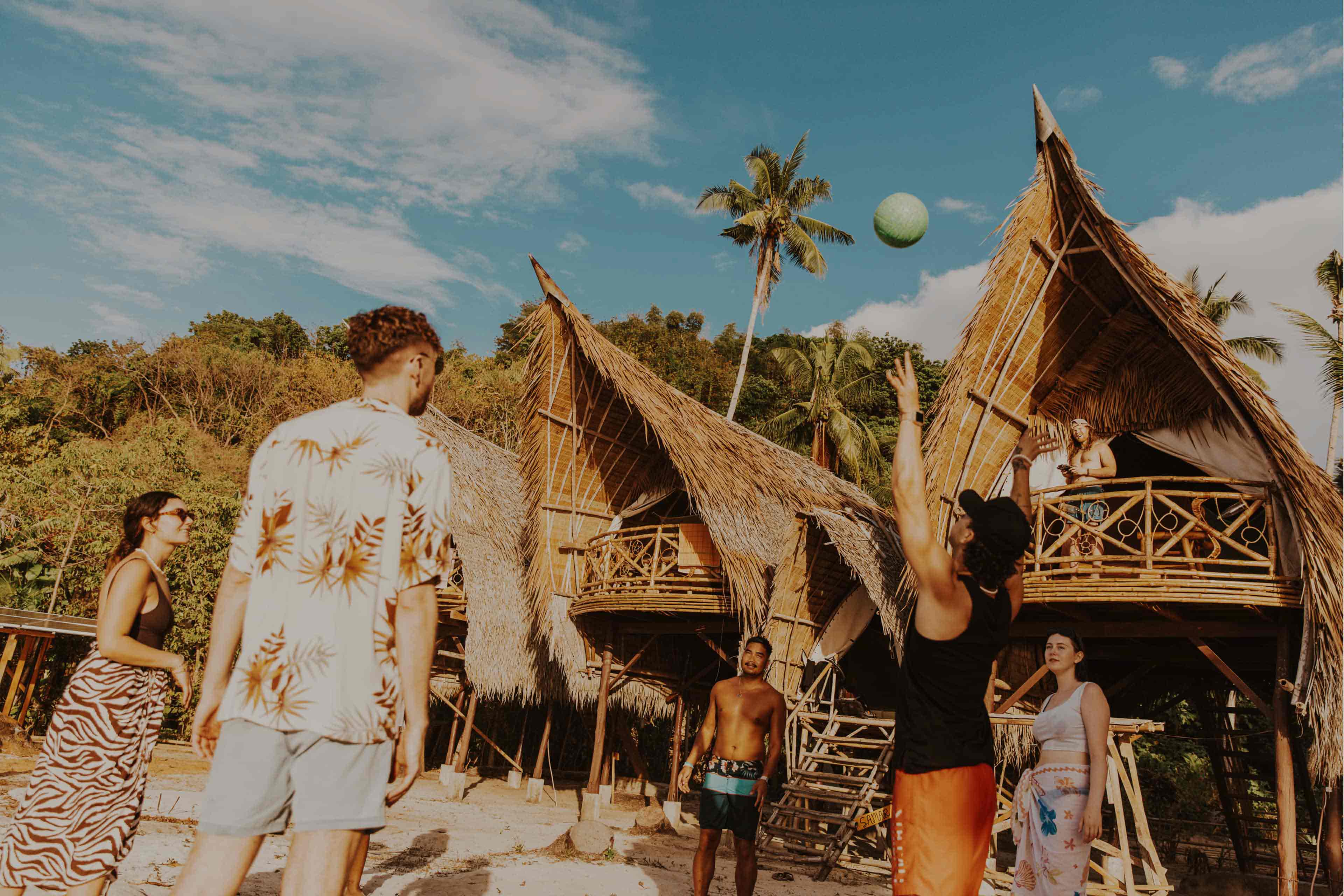 Group playing volleyball near traditional huts in the Philippines