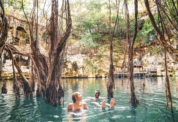 A Couple Swimming in the Water Surrounded by Rocks and Plants