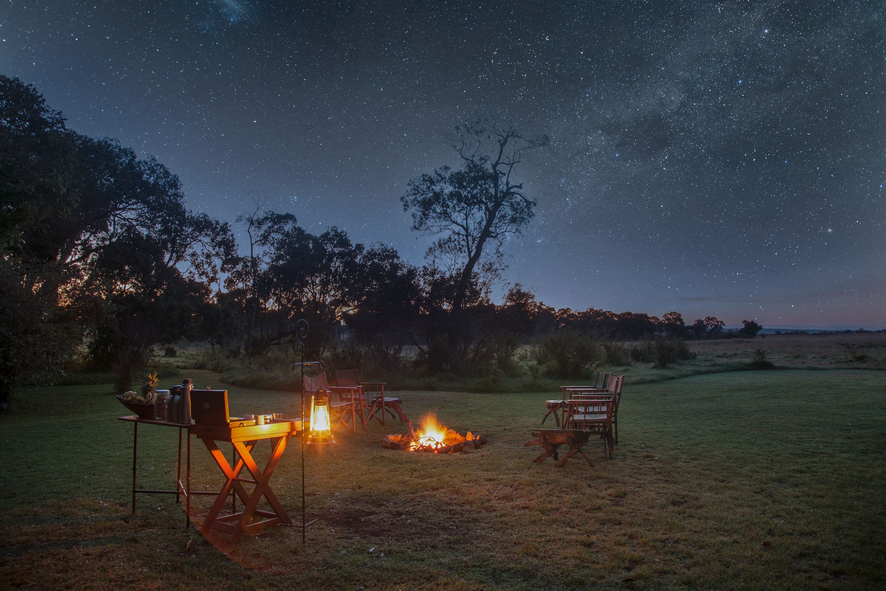 Chairs around a fire at nighttime at a safari camp in Kenya.
