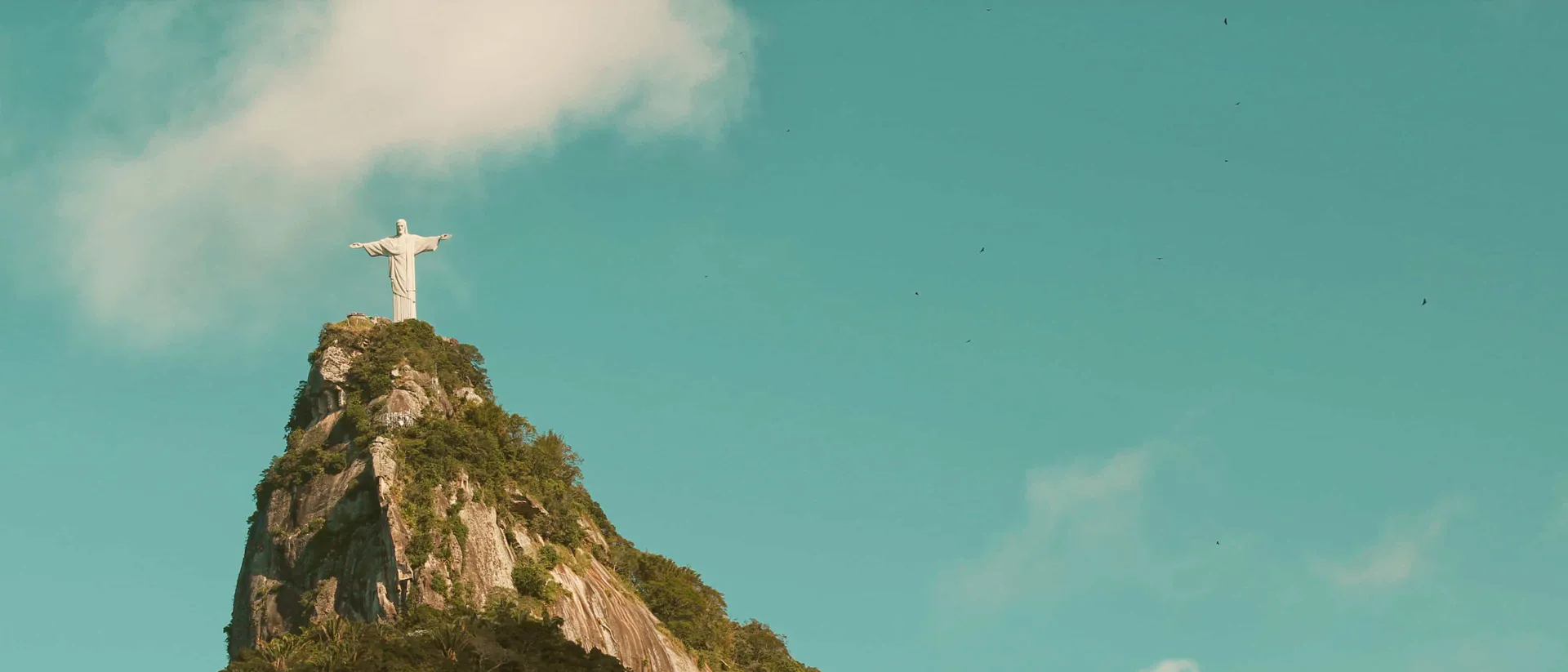 Christ the Redeemer statue crowning the forested peak of Corcovado mountain in Rio de Janeiro, Brazil.