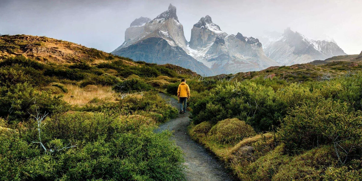 Traveller hiking through Patagonia with dramatic mountain peaks on the Contiki Active Patagonia Tour
