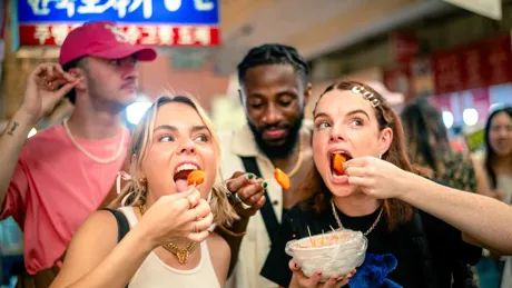 Group Of Young Travelers Eating Street Food in South Korea