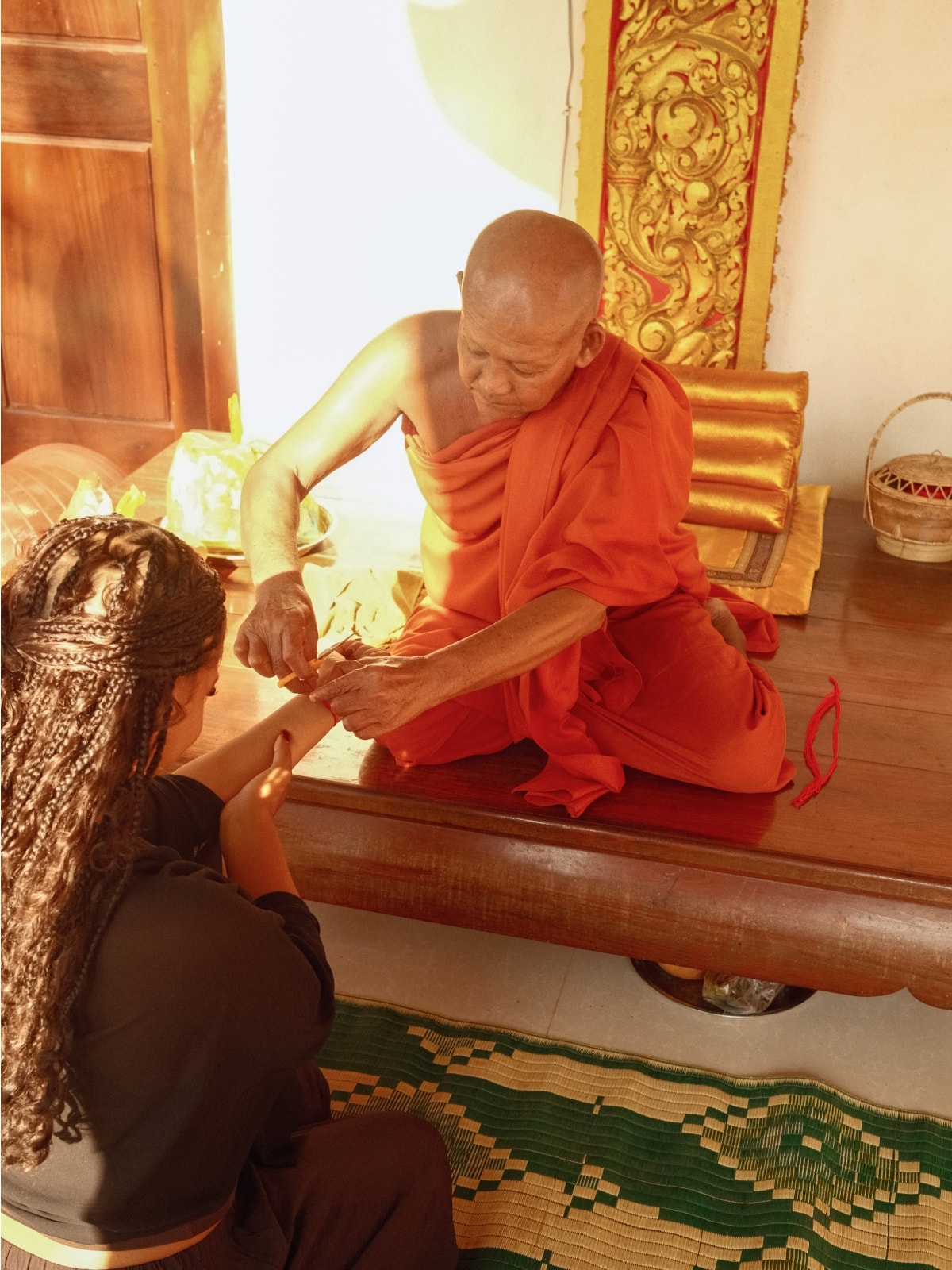 Buddhist monk tying a traditional blessing bracelet on a traveller at a temple in Cambodia.