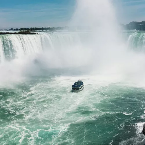 Boat sails through the mist beneath Niagara Falls on Contiki's Canada: Toronto, Niagara & Quebec Tour, experiencing one of Canada's most iconic natural wonders