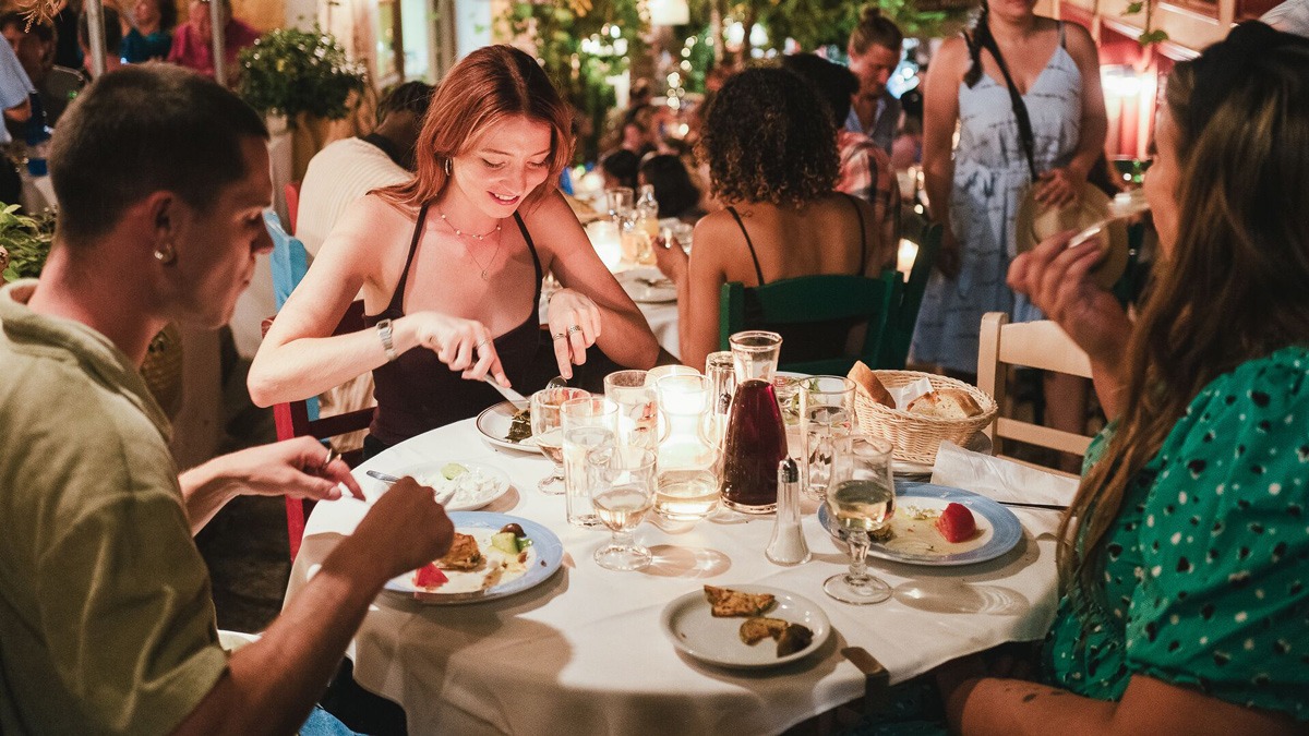 Friends enjoying dinner at a restaurant warm weather in Greece.