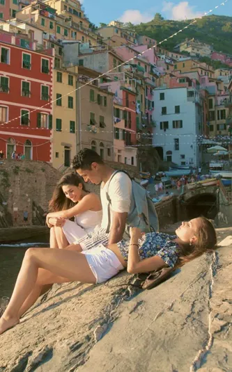 Three people relaxing by the sea in Riomaggiore, Cinque Terre - Contiki Tuscany, Milan & Venice Tour
