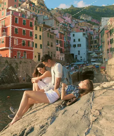 Three people relaxing by the sea in Riomaggiore, Cinque Terre - Contiki Tuscany, Milan & Venice Tour