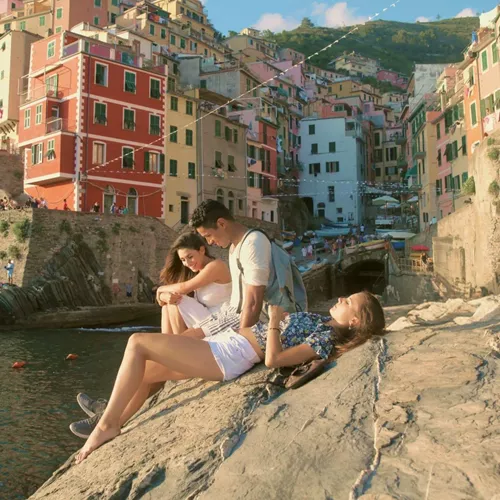 Three people relaxing by the sea in Riomaggiore, Cinque Terre - Contiki Tuscany, Milan & Venice Tour