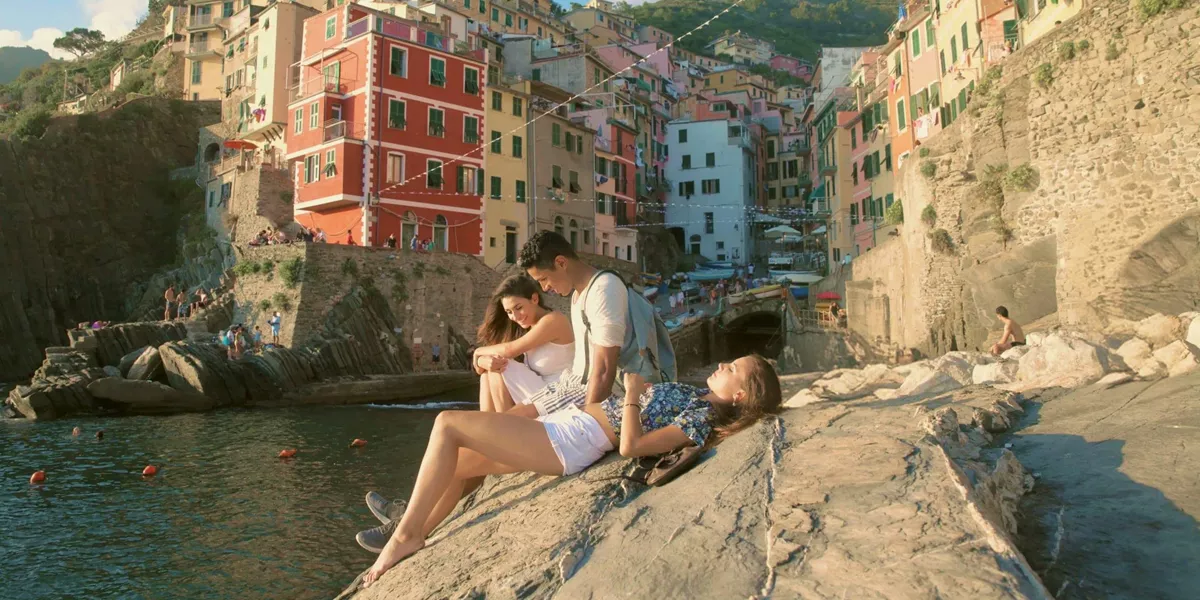 Three people relaxing by the sea in Riomaggiore, Cinque Terre - Contiki Tuscany, Milan & Venice Tour