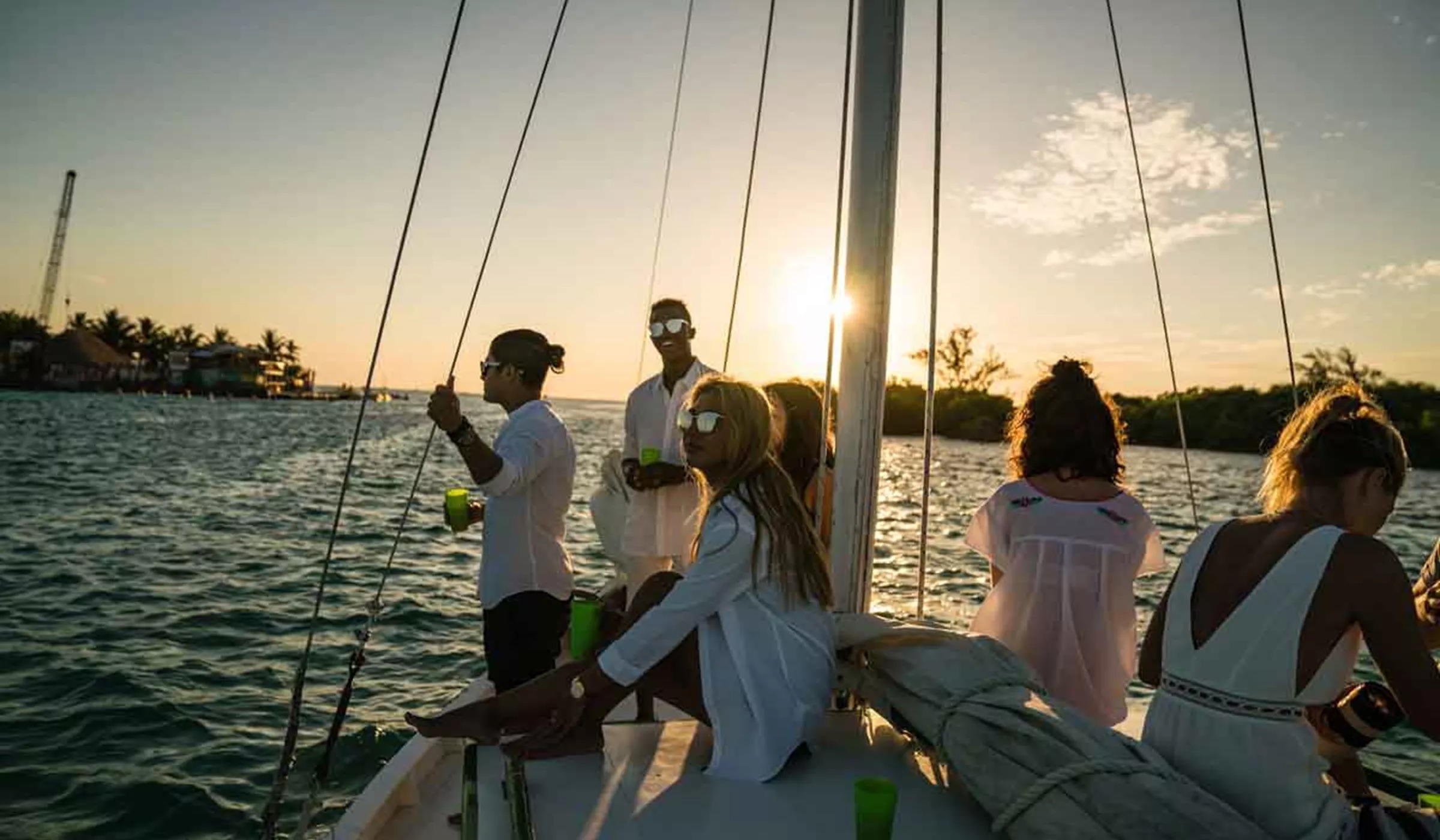 A group of people sitting in a boat and enjoying sunset in Belize. 
