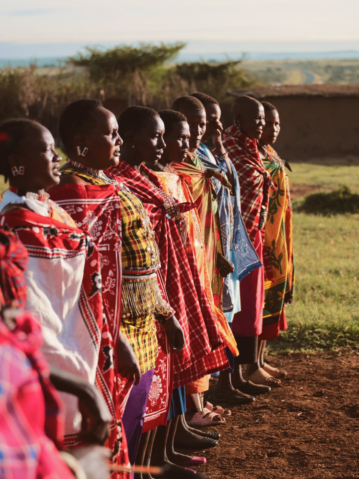 Maasai women in colourful traditional dress standing in a line during a cultural gathering in Kenya.
