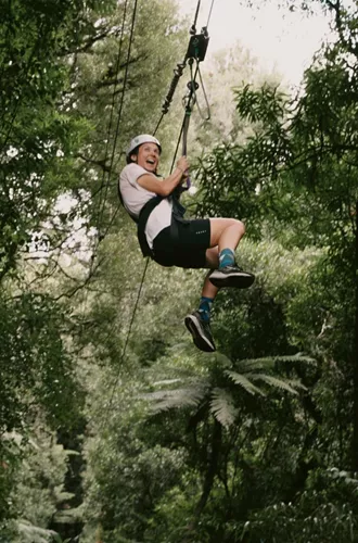 Traveller ziplining through native forest in New Zealand - Contiki North Island & Kaikōura Tour