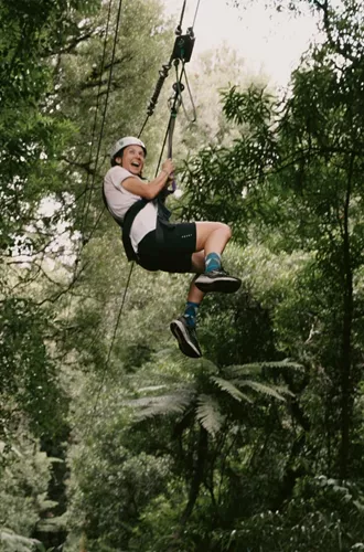 Traveller ziplining through native forest in New Zealand - Contiki North Island & Kaikōura Tour