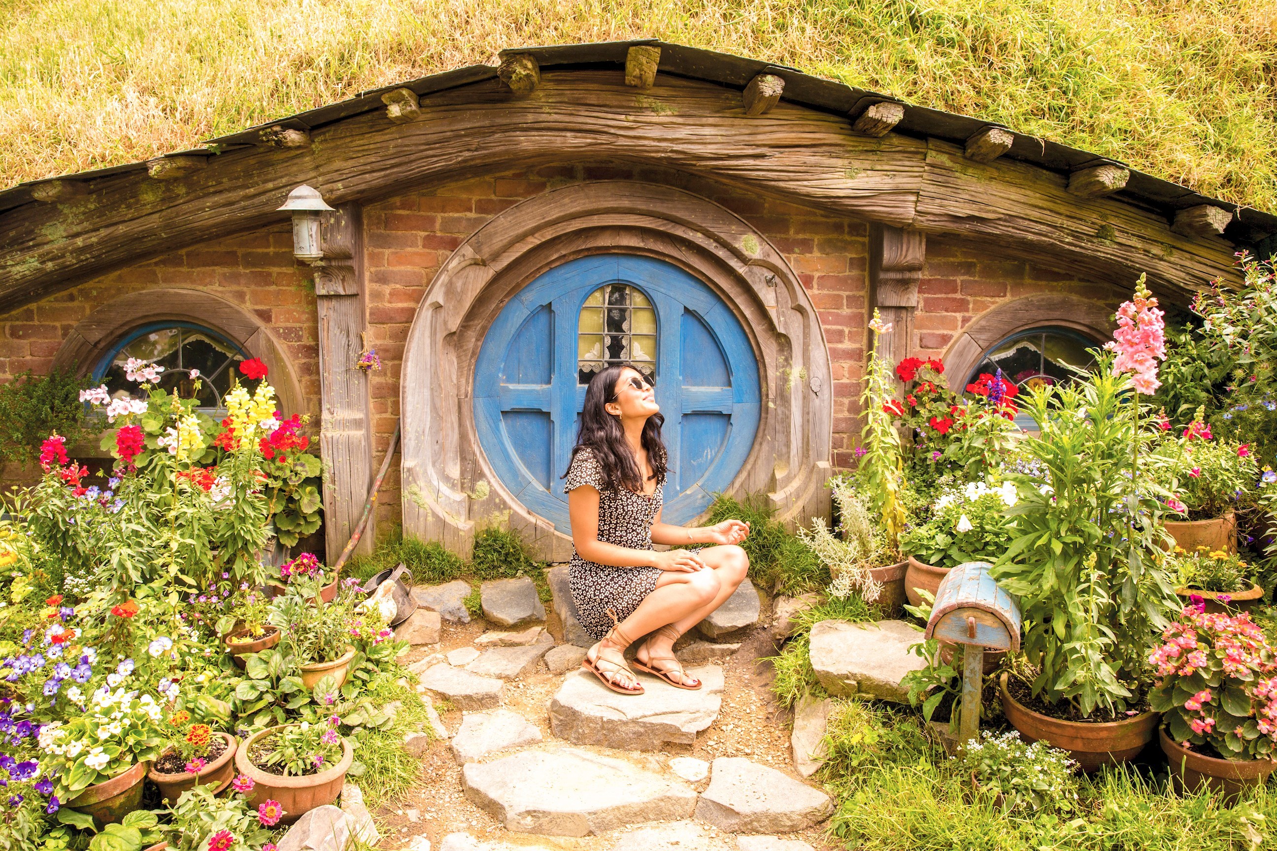 Traveller sitting in front of a hoobit-hole in Rotorua, New Zealand