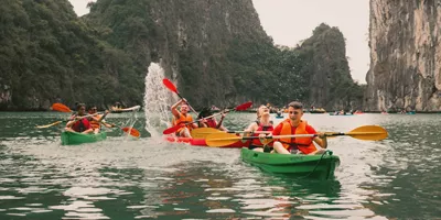 Young travellers kayaking between towering limestone karsts in Ha Long Bay Vietnam - Contiki Best of Vietnam Tour