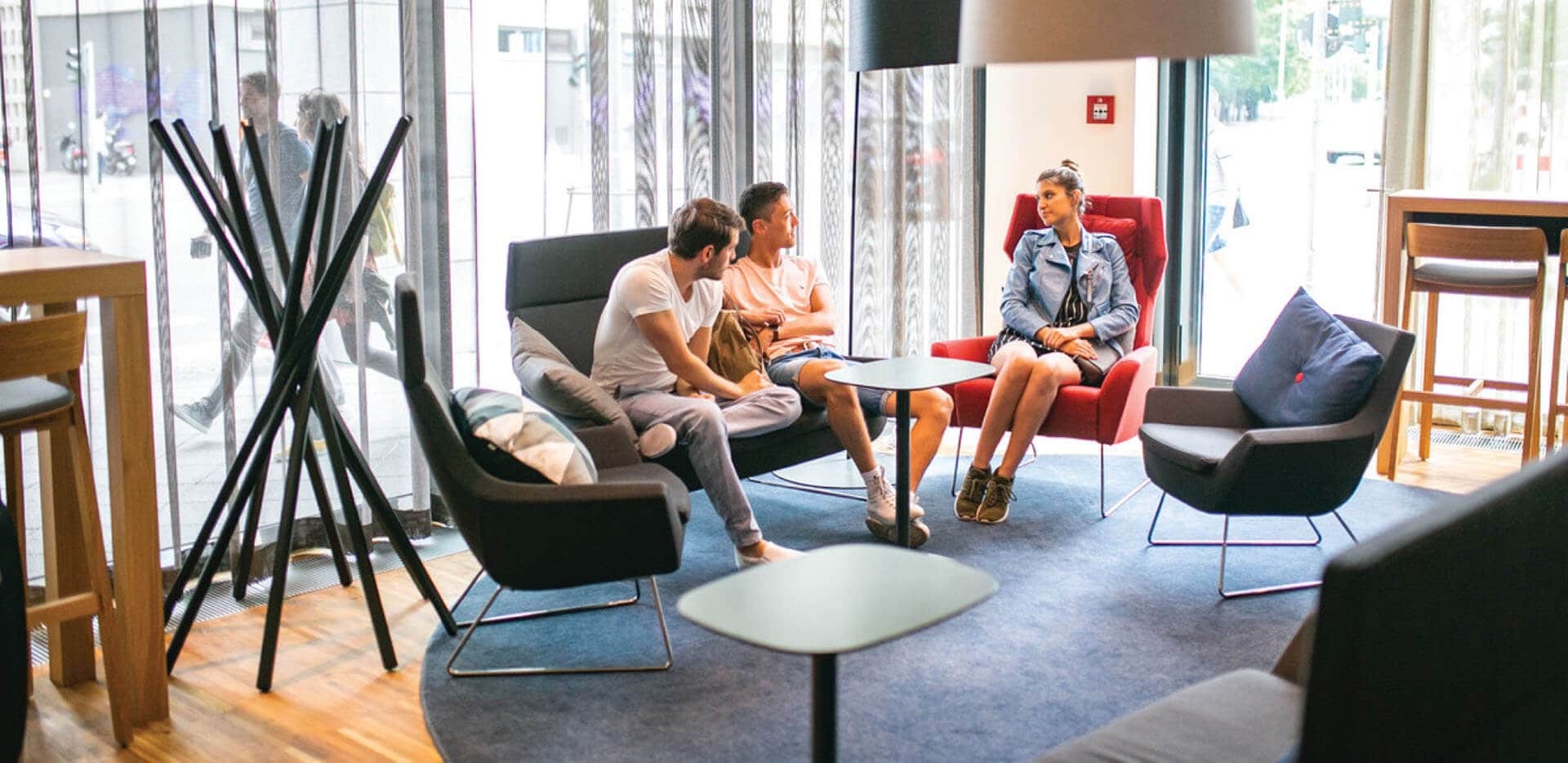 Guests relaxing on armchairs in modern style living room of  Plus Hostel Berlin