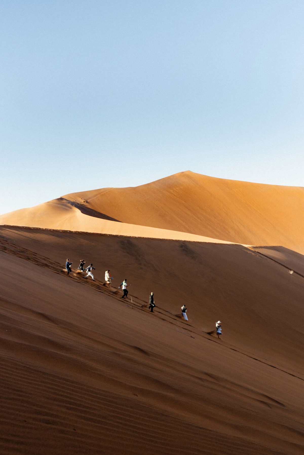 Denser dunes with people walking in Namibia.