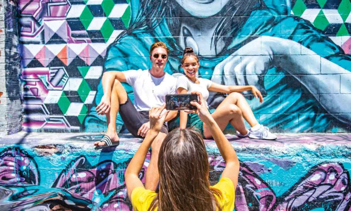 Young Travelers Taking Photo In Front Of Graffi On A City Break