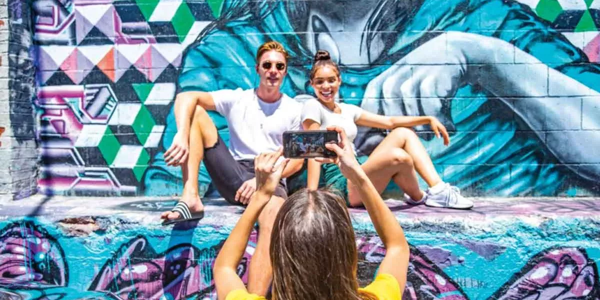 Young Travelers Taking Photo In Front Of Graffi On A City Break