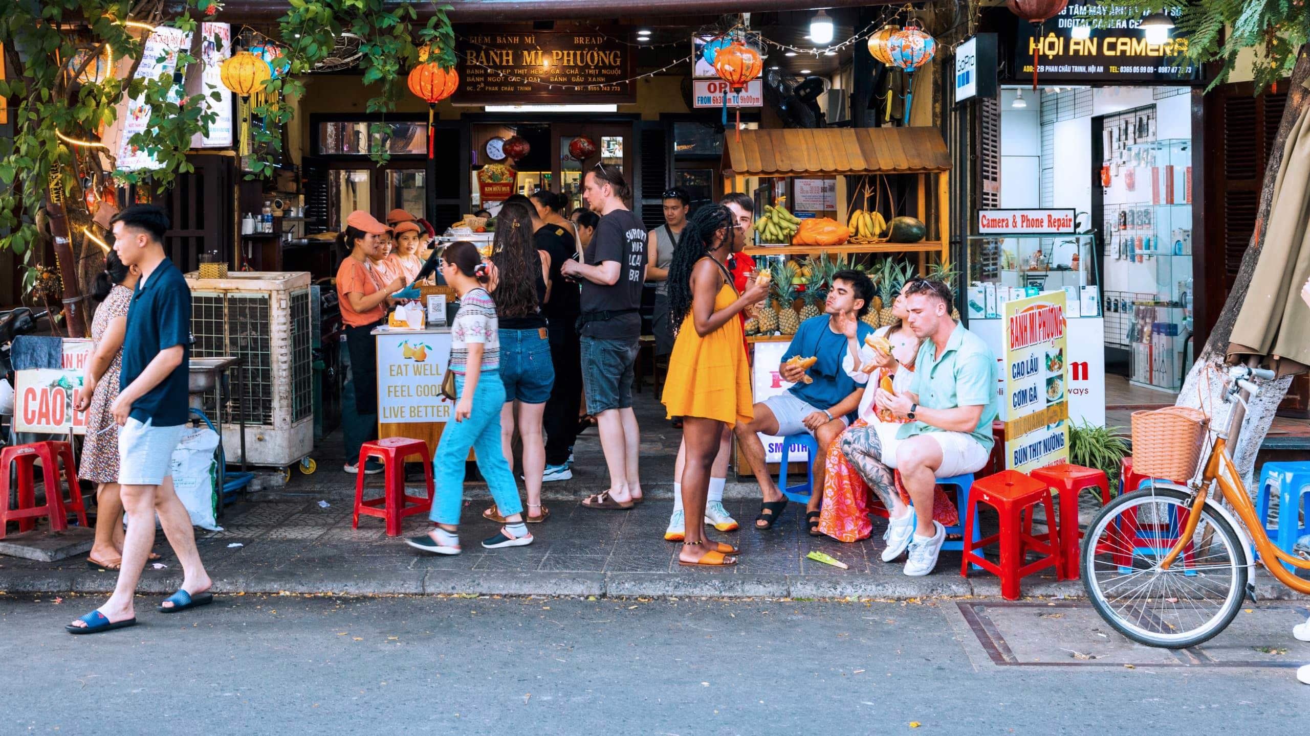 Travellers eating bánh mì outside the famous Bánh Mì Phượng shop in Hội An Vietnam - Contiki Vietnam Tour