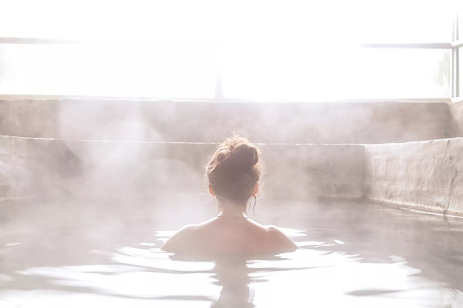 Woman in a steaming outdoor bath.