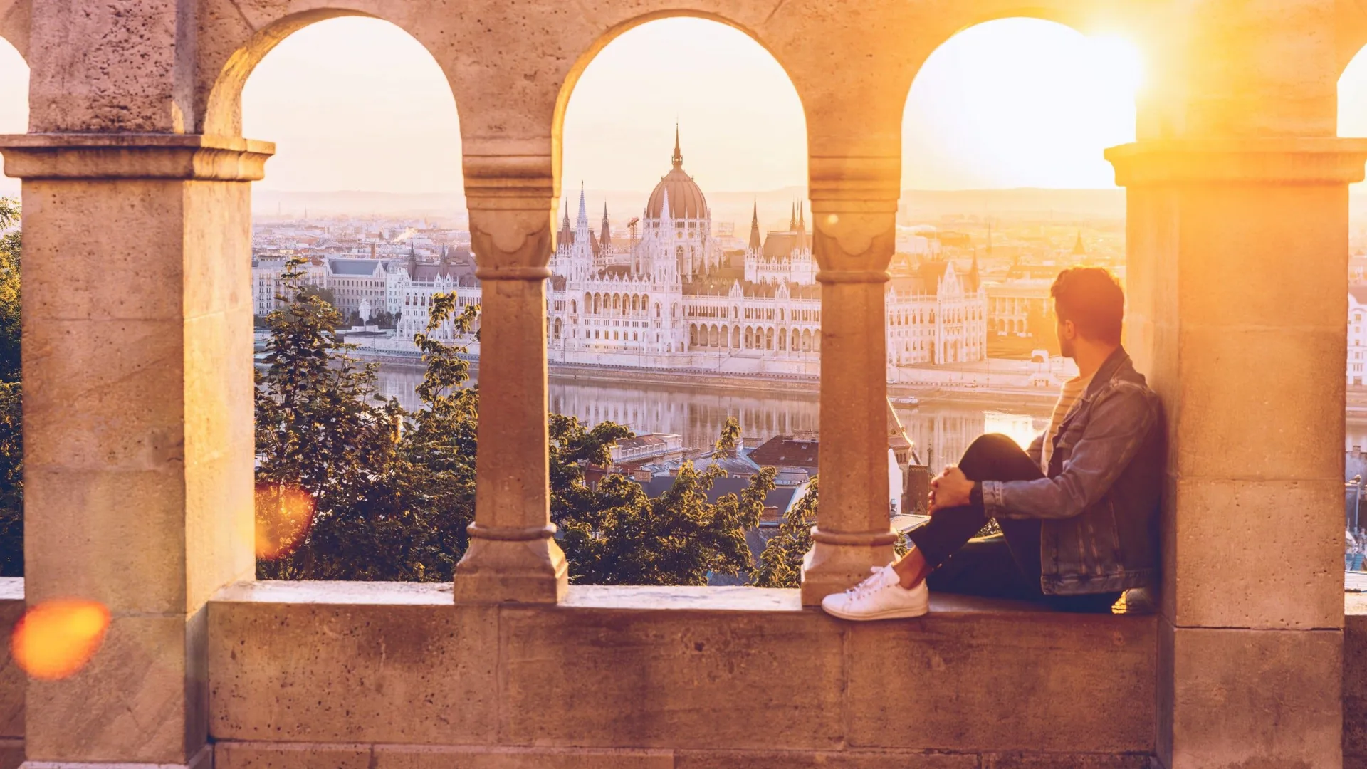 A Contiki traveller watches the sunset over the Hungarian Parliament Building from Fisherman's Bastion in Budapest on the London to Vienna Trail