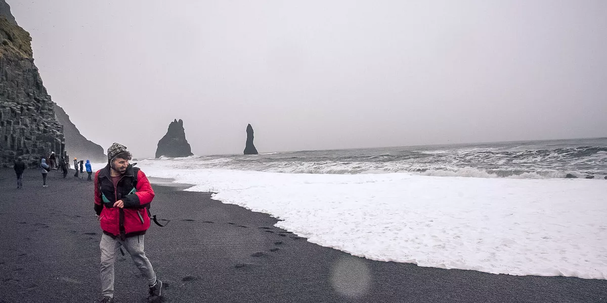 Man Walking On A Black Sand Beach