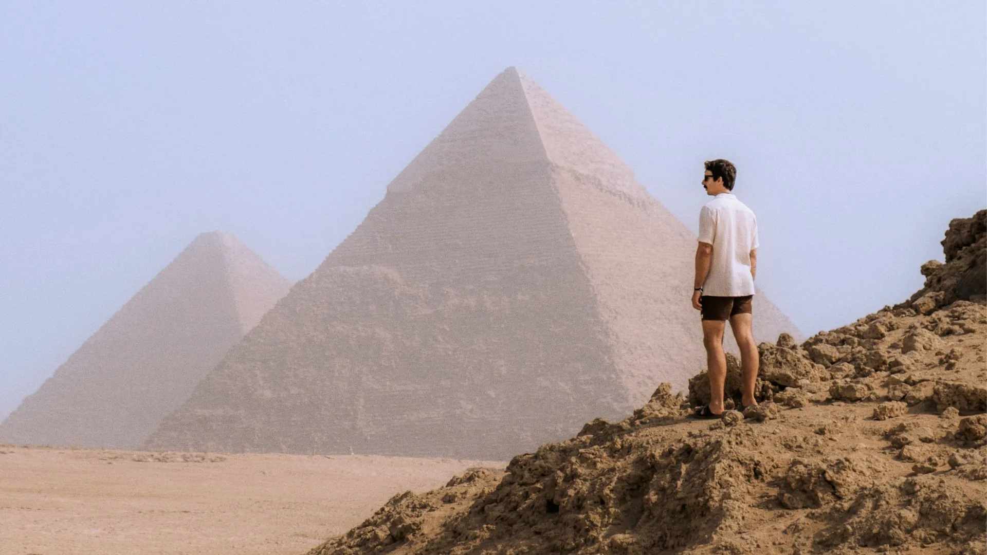 A Contiki traveller stands in the desert overlooking the Pyramids of Giza, taking in one of Egypt's most iconic ancient landmarks - Egypt Explorer Tour