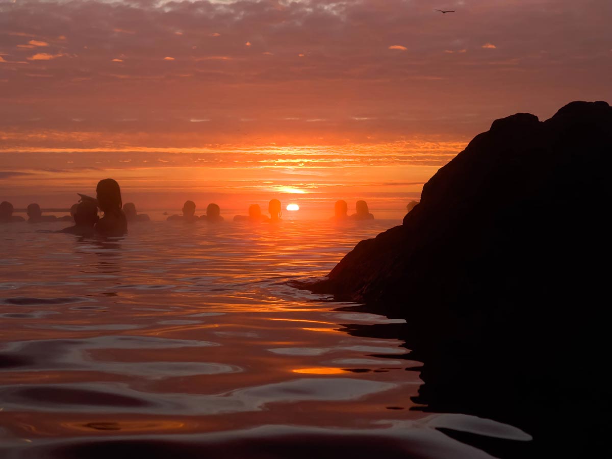 People enjoying a sunset in a warm natural pool in Iceland.
