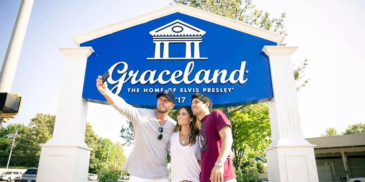 Three People Takig A Photo In Front Of Graceland Sign