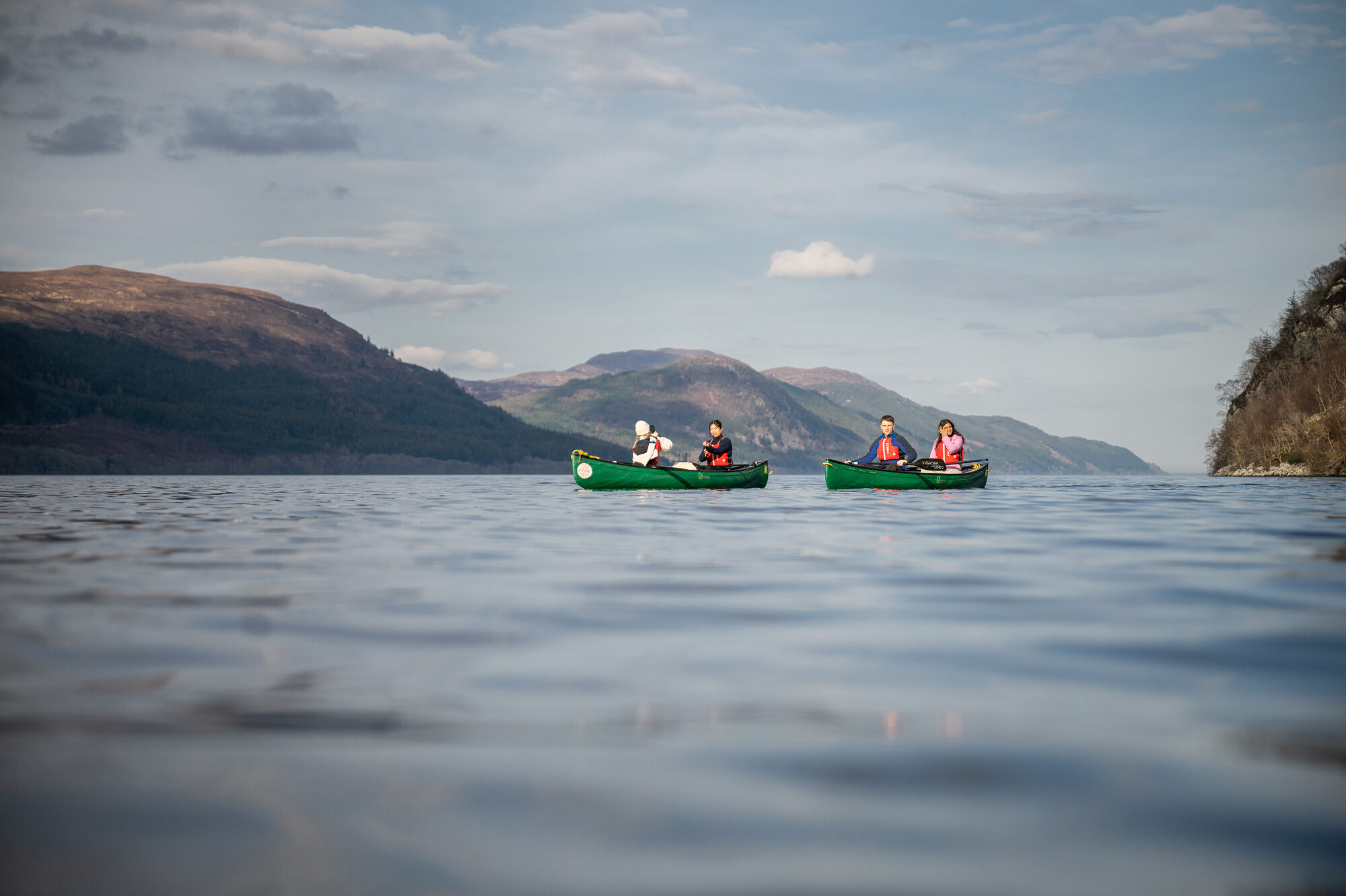 People in boats at a lake mountains at the back