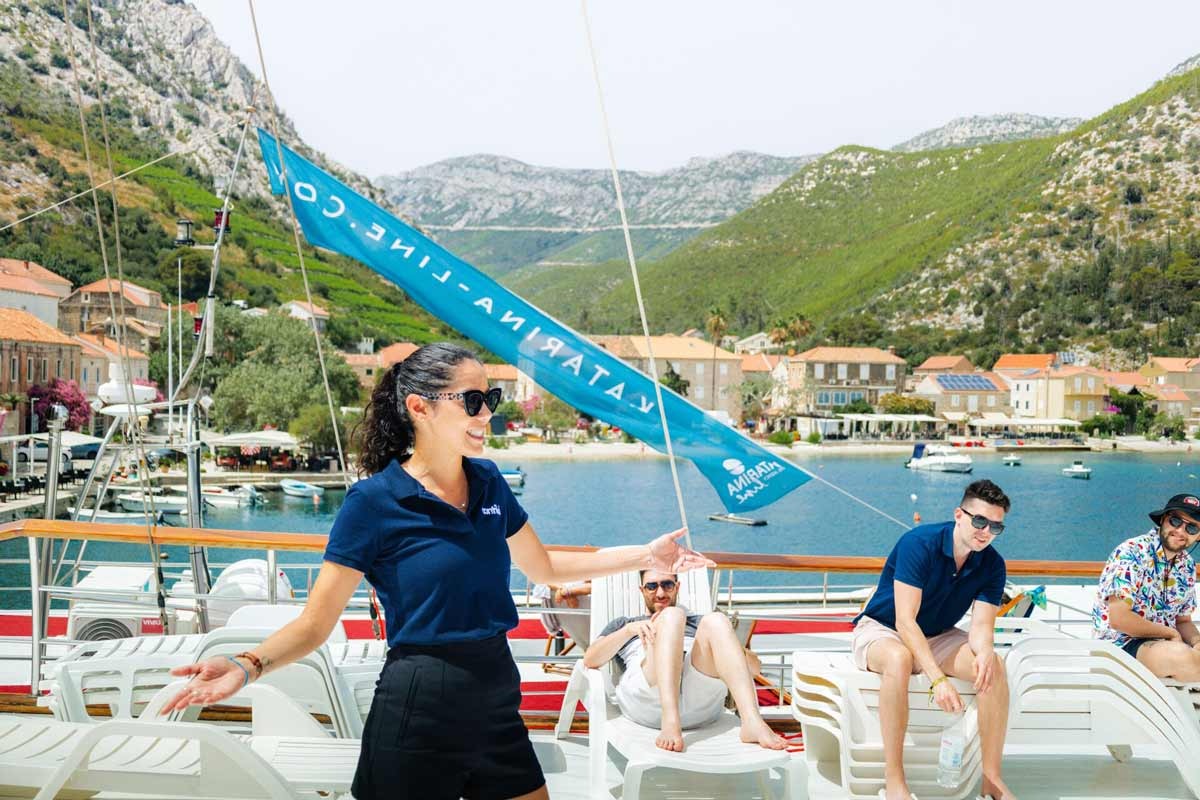 People enjoying a sunny day on the deck of a boat green mountains at the back in Croatia.
